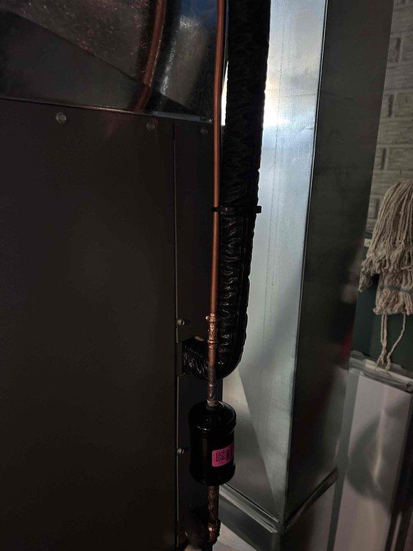 Completed full HVAC system installation including indoor air handler unit and outdoor condensing unit. Installed new air handler in mechanical room with proper copper refrigerant line connections and black insulated line set, integrated silver metallic supply ductwork for air distribution throughout the residence. Mounted outdoor condensing unit on exterior with appropriate clearances from building, installed white PVC condensate drain line with proper pitch and termination, added splash guard at grade level to prevent water pooling. System tested and verified operational with all components functioning within manufacturer specifications.