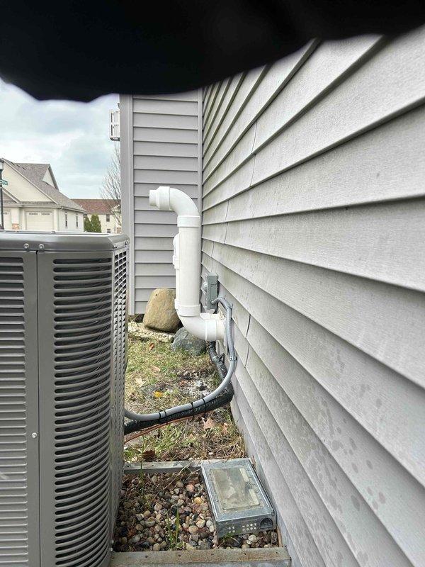 Completed full HVAC system installation including indoor air handler unit and outdoor condensing unit. Installed new air handler in mechanical room with proper copper refrigerant line connections and black insulated line set, integrated silver metallic supply ductwork for air distribution throughout the residence. Mounted outdoor condensing unit on exterior with appropriate clearances from building, installed white PVC condensate drain line with proper pitch and termination, added splash guard at grade level to prevent water pooling. System tested and verified operational with all components functioning within manufacturer specifications.