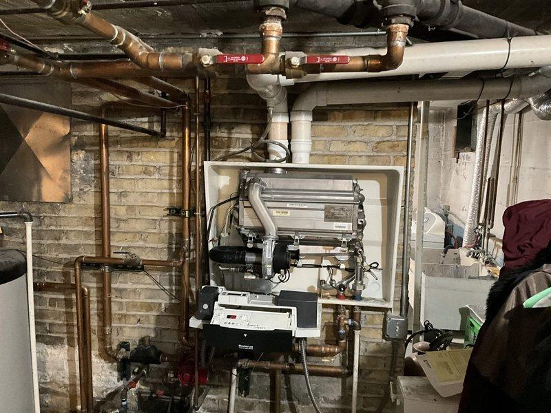 Conducted comprehensive assessment of existing basement heating system and water heater installation. Documented current HVAC equipment configuration including air handler unit with control systems, exposed copper supply and return piping with shut-off valves, and PVC condensate drainage. Evaluated water heater condition and plumbing connections, noting all mechanical components, valve locations, and system integration points for preparation of boiler replacement estimate.
