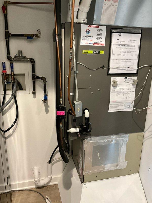 Completed HVAC estimate for furnace and air handler replacement in residential utility space. Assessed existing gray metal furnace unit with visible service history and documentation, along with overhead air handler installation featuring condensate management system. Evaluated current plumbing connections including copper lines with shutoff valves, PVC drainage configuration, and electrical infrastructure to provide comprehensive replacement recommendations for updated high-efficiency equipment.
