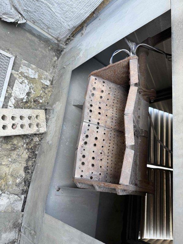 Completed commercial RTU inspection and documentation. Unit exhibited significant corrosion on drain pan with extensive rust deterioration throughout the perforated surface, indicating prolonged moisture exposure and potential drainage issues. Electrical wiring connections showed heavy dust and debris accumulation on terminal blocks and throughout the compartment, with cobweb buildup on concrete surfaces and wire runs. Photographed corroded drain pan assembly, insulation condition, and electrical wiring connections for maintenance records and recommended follow-up repairs to address pan replacement and compartment cleaning to prevent potential electrical issues from contamination.
