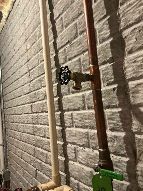 Completed inspection and documentation of exposed plumbing system featuring copper supply lines and PVC drain lines mounted on basement wall. Verified operation of brass shut-off valves with cross-handle configuration and confirmed proper identification tagging of water supply lines per code requirements.