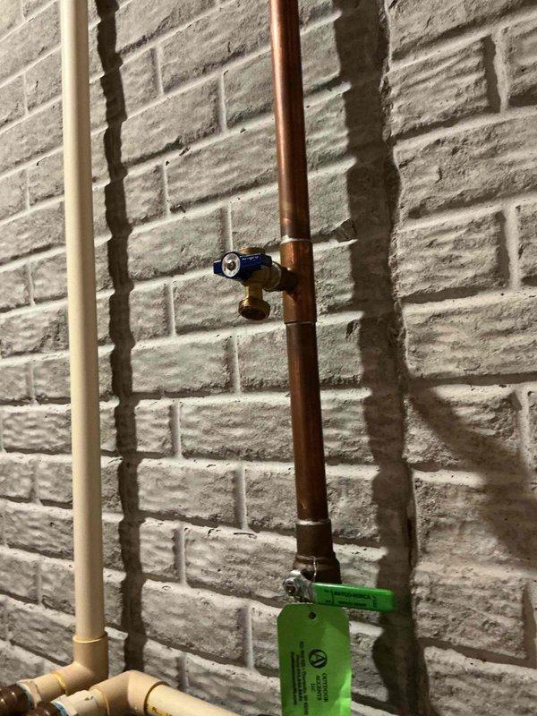 Completed inspection and documentation of exposed plumbing system featuring copper supply lines and PVC drain lines mounted on basement wall. Verified operation of brass shut-off valves with cross-handle configuration and confirmed proper identification tagging of water supply lines per code requirements.