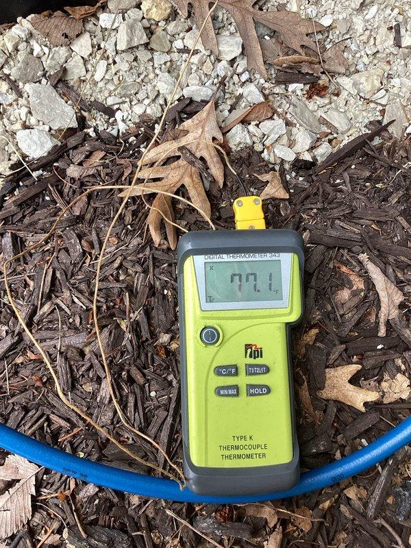 Completed system start-up for newly installed HVAC equipment. Connected manifold gauge set to condenser unit and verified refrigerant pressures across the system, with readings showing proper charge levels on both low-side (blue gauge) and high-side (red gauge) indicators. Measured ambient and system temperatures using digital thermometer, recording 77.1°F to establish baseline operating conditions. All gauges indicated normal operating parameters, confirming successful installation and proper system function upon initial start-up.