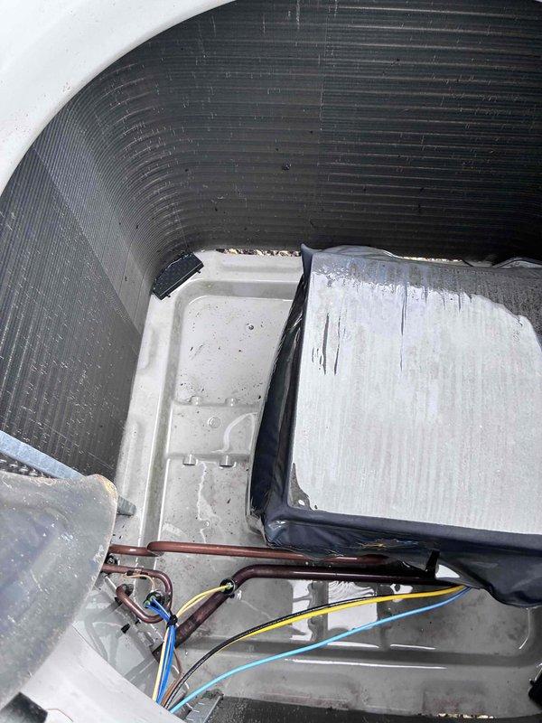 Completed comprehensive HVAC tune-up on outdoor heat pump unit. Removed top cover to access internal components, inspected compressor cavity, condensate drain pan, and refrigerant lines for proper operation. Verified electrical connections, tested control wiring and valve assembly, and confirmed all mechanical components are functioning within normal parameters.