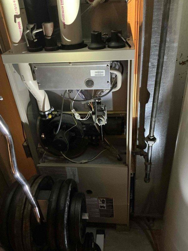 Completed comprehensive HVAC system evaluation for equipment replacement estimate. Documented existing air handler unit installed in attic space with dark green metal casing and assessed heating system components including dual expansion tanks, internal piping, valves, and control interfaces housed in white cabinet enclosure. Photographed current equipment configuration, mounting systems, ductwork connections, and mechanical components to provide detailed replacement specifications and system upgrade recommendations.