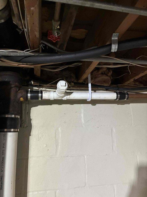 Conducted inspection of basement plumbing infrastructure including PEX water supply lines, PVC drain lines, and associated mounting hardware. Documented existing pipe routing, support systems, and junction connections between wooden floor joists and along foundation wall to assess current installation condition and identify any maintenance requirements.