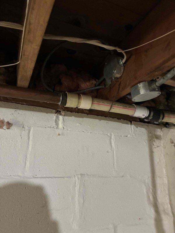 Conducted inspection of basement plumbing infrastructure including PEX water supply lines, PVC drain lines, and associated mounting hardware. Documented existing pipe routing, support systems, and junction connections between wooden floor joists and along foundation wall to assess current installation condition and identify any maintenance requirements.