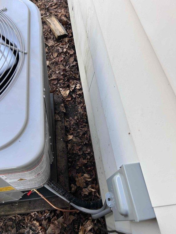 Completed installation of new Carrier air conditioning system with matching evaporator coil at residential property. Installed outdoor condensing unit on elevated platform against exterior wall, ran refrigerant lines and electrical connections through conduit to disconnect box mounted on building siding, and positioned unit for optimal airflow and serviceability. System was pressure tested, evacuated, charged to manufacturer specifications, and verified operational with all safety controls functioning properly.