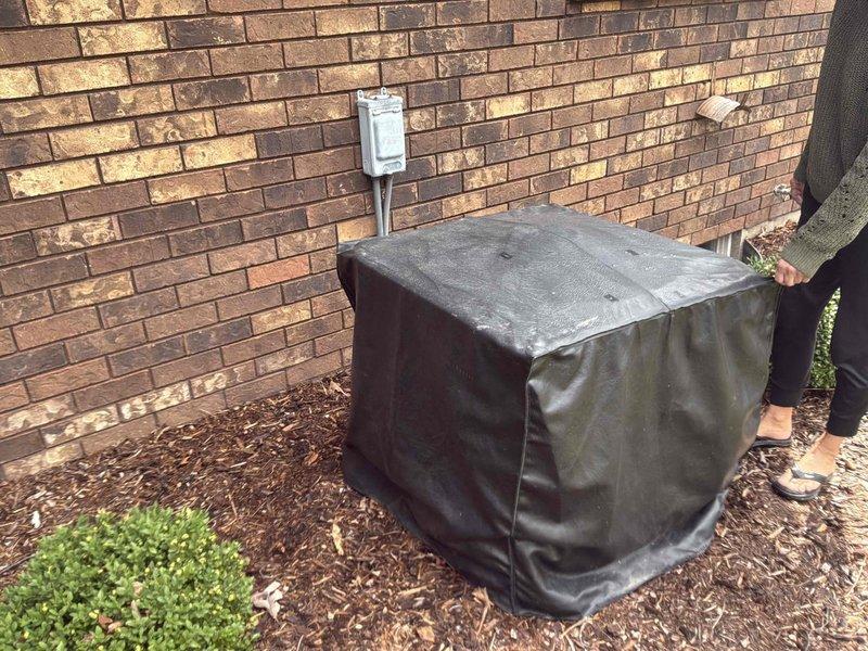 Conducted comprehensive site evaluation for complete HVAC system replacement at residential property. Assessed existing outdoor condensing unit positioned against brick exterior wall, documented current equipment configuration including electrical disconnect box, conduit routing, and refrigerant line placement. Evaluated installation area conditions including mulch bedding, patio brick surface, and clearance requirements for new equipment placement. Photographed existing unit with protective cover in place and exposed condenser unit to document current system specifications, mounting location, and utility connections. Provided detailed replacement estimate covering removal of existing equipment and installation of new high-efficiency HVAC system with properly sized condensing unit, updated electrical connections, and compliant refrigerant line routing across herringbone brick patio surface.