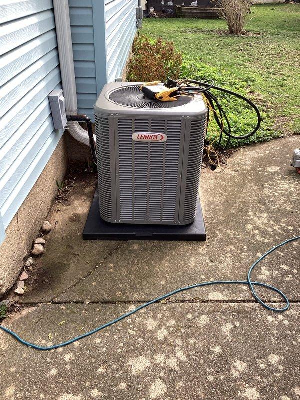 Completed installation of new Lennox air conditioning condensing unit and evaporator coil at residential property. Unit was positioned on existing concrete pad adjacent to building with proper clearances maintained, refrigerant lines connected and insulated, electrical connections verified with multimeter testing, and system commissioned to manufacturer specifications.
