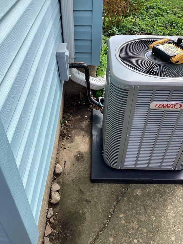 Completed installation of new Lennox air conditioning condensing unit and evaporator coil at residential property. Unit was positioned on existing concrete pad adjacent to building with proper clearances maintained, refrigerant lines connected and insulated, electrical connections verified with multimeter testing, and system commissioned to manufacturer specifications.