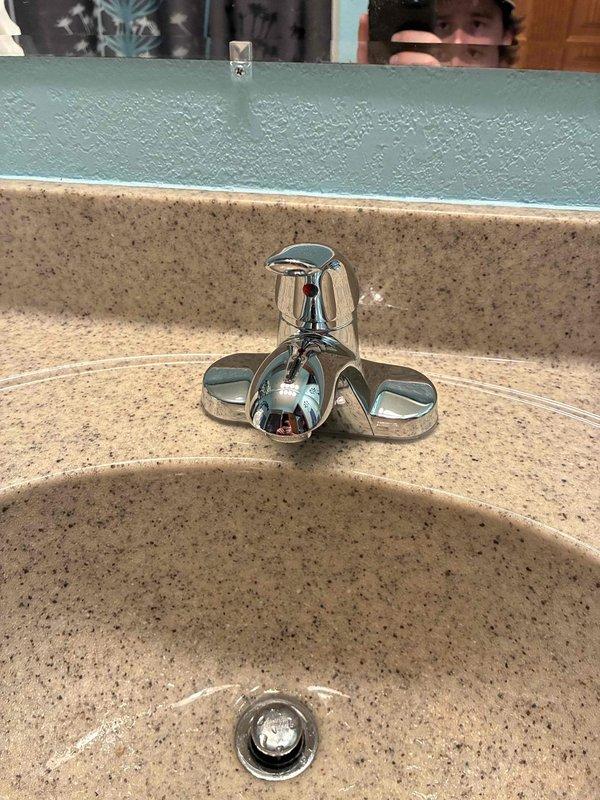 Completed installation of chrome cross-handle faucet assembly on bathroom sink with beige composite countertop. Connected new braided flexible supply lines from wall-mounted shut-off valves to faucet, ensuring proper water flow to fixture. Verified all connections are secure, tested for leaks, and confirmed proper drainage through existing white PVC P-trap assembly.