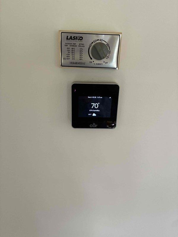 Completed comprehensive tune-up and performance evaluation on residential HVAC system. Performed diagnostic testing using calibrated digital instrumentation to verify system operation, inspected control wiring and electrical connections within air handler unit, and confirmed proper functionality of both the LASKO outdoor temperature control panel and digital thermostat displaying accurate temperature and humidity readings at 70°F and 67% respectively.