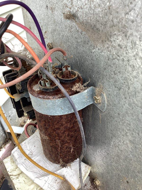 # HVAC Service Report - No Cool Condition

Responded to no cooling complaint on residential air conditioning system over 10 years old. Upon arrival, performed visual inspection of outdoor condensing unit and electrical components. Found heavily corroded dual run capacitor with significant rust deterioration affecting the metal casing and mounting hardware. Capacitor showed extensive oxidation from prolonged environmental exposure, indicating component was well beyond serviceable life.

Connected manifold gauges to service ports and performed system diagnostics. Verified compressor and condenser fan motor operation. Due to severe corrosion on existing capacitor and compromised electrical connections, determined immediate replacement was necessary to restore cooling function and prevent potential system failure.

Disconnected power to unit and safely removed failed capacitor. Cleaned terminal connections and inspected wiring harness for additional damage from corrosion. Installed new dua