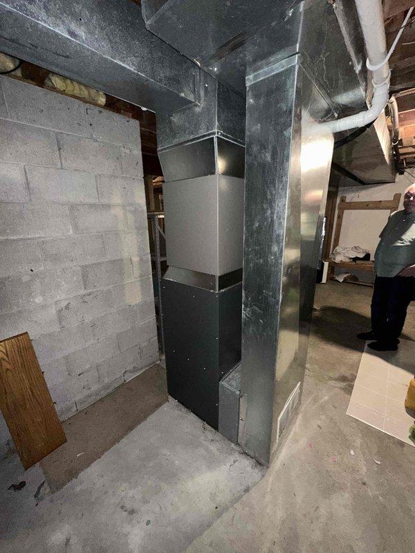 Completed full HVAC system replacement in residential basement utility area. Installed new furnace unit with associated vertical ductwork system including metal plenum boxes and galvanized duct sections running floor to ceiling. Configured white PVC condensate drain and venting lines for proper furnace operation. System has been tested and is fully operational.