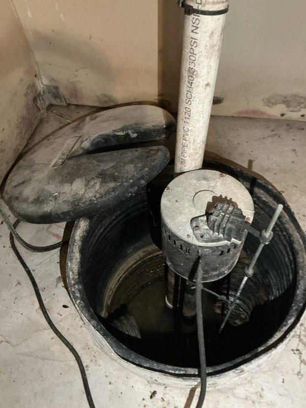 # Sump Pump Inspection and Service

Performed comprehensive inspection and service of existing sump pump system installed in basement utility area. Verified proper operation of submersible sump pump unit within circular pit equipped with black plastic liner set into concrete floor. Tested float switch mechanism for appropriate activation and deactivation at correct water levels. Confirmed secure attachment of float assembly to pump body and verified unobstructed movement throughout full range of motion.

Inspected white PVC discharge pipe for proper vertical alignment and secure mounting. Verified discharge pipe bracket and clamp assembly maintaining stable positioning. Examined two-piece sump pit cover for proper fit around discharge piping, ensuring adequate access for future maintenance while preventing debris entry into pit.

Assessed overall system functionality in conjunction with visible basement mechanical equipment, including pressure tank, water treatment systems, and associa