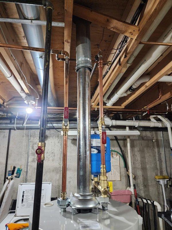 Completed installation of new water heating system in basement mechanical room. Installed vertical cylindrical water heater with associated copper piping connections, pressure relief components, and blue expansion tank. Configured all supply and return lines with proper valving, integrated system with existing plumbing infrastructure including gas lines and shut-off valves. Ensured all connections meet code requirements and verified system operation upon completion.