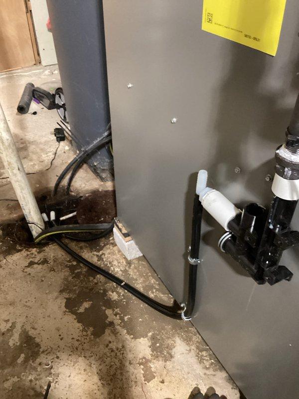 Completed furnace installation in basement utility area. New gray air handler unit installed on concrete floor with proper mounting and support brackets. Connected black refrigerant lines and white PVC condensate piping with appropriate fittings. Installed electrical wiring and verified all connections secure. Performed system diagnostics using calibrated digital manometer, confirming proper pressure readings at -35.80. Inspected blower motor assembly and internal components to ensure proper operation. All piping, wiring, and mechanical components installed to manufacturer specifications and code requirements. Unit tested and operational.
