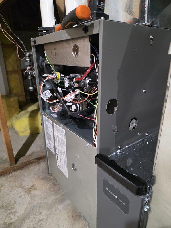 Completed full furnace installation in basement utility area. New gas furnace unit was installed with proper venting configuration using white PVC piping system, connected to existing ductwork distribution system with black metal supply plenum. All internal components including blower motor, control circuitry, capacitors, and burner assembly were installed and wired according to manufacturer specifications. Unit was tested and verified operational.