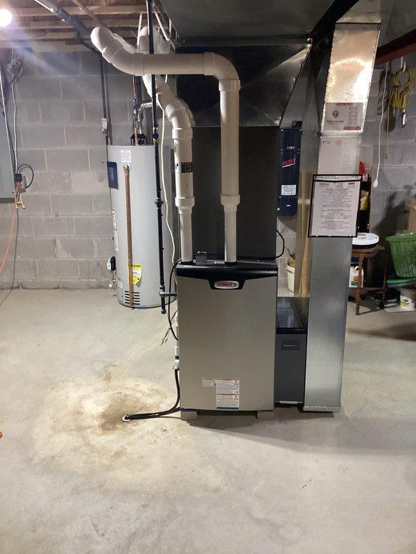 Completed full HVAC system installation in basement mechanical room, including new Lennox furnace unit, air handler, and associated ductwork. Installed white PVC condensate drain piping with proper pitch and trap configuration, secured with appropriate mounting brackets to structural supports. Routed large-diameter supply and return ductwork from furnace to distribution points, ensuring proper connections and sealed joints. All equipment positioned per manufacturer specifications with adequate clearance for service access. System tested and verified operational upon completion.