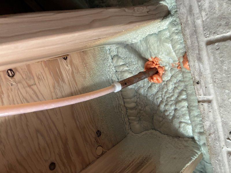 Responded to diagnostic call for reported broken pipe in basement near hose bib connection. Upon inspection, identified copper piping running through recently insulated area with spray foam application. Investigated moisture concerns around iron curtain water treatment system, determining visible wetness was likely condensation rather than active pipe failure. Documented existing plumbing configuration including copper supply lines, fittings, and connections in unfinished basement space with exposed framing and concrete block foundation walls.
