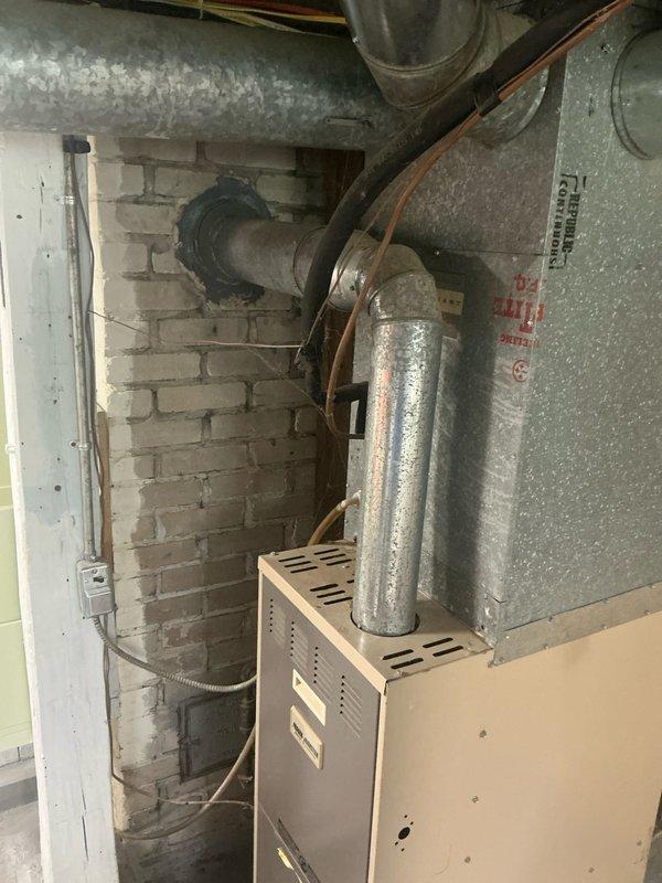 Conducted furnace replacement estimate for residential HVAC system located in basement utility area. Evaluated existing furnace unit with two-tone cabinet configuration, assessed current ductwork connections including galvanized metal supply and return ducts, and documented mechanical room infrastructure including ventilation piping and existing flue system. Provided comprehensive replacement options and recommendations based on current equipment condition and system layout.