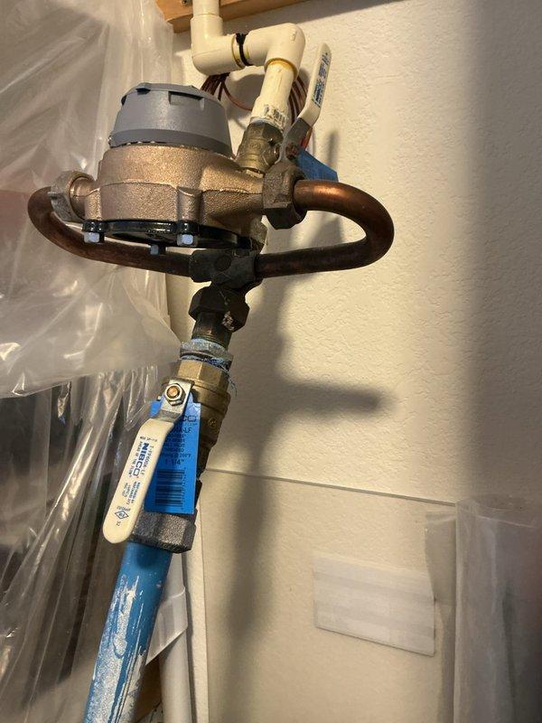 Completed inspection for sprinkler system meter installation requiring new water meter and approximately 5 feet of supply piping. Assessed existing plumbing configuration including water pressure regulator assembly with mixed piping materials (PVC, copper, and PEX), and evaluated ceiling cavity access point where copper supply lines with shut-off valve are located above insulation and structural framing. Documented current system conditions and photographed installation areas to provide accurate estimate for meter replacement and piping extension work.
