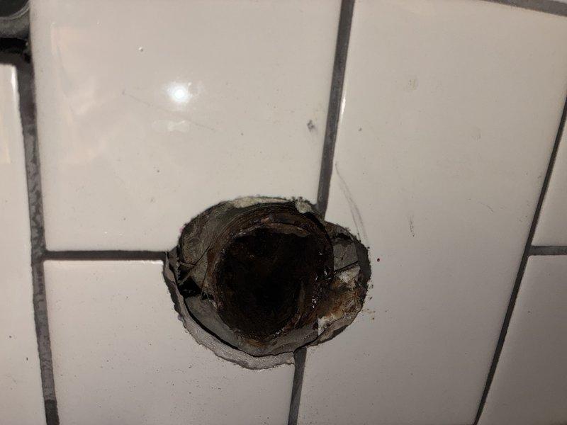 Responded to service call for deteriorating bathroom plumbing affecting tenant occupancy. Upon arrival, performed comprehensive diagnostic inspection of restroom plumbing system. Identified compromised pipe connections behind tiled wall surface with visible water damage and material deterioration around access point. Accessed plumbing through existing wall opening, revealing damaged pipe sections with corrosion and structural weakness. Evaluated PVC supply lines, shower valve assembly, and braided metal supply hoses for integrity. Found multiple areas of concern including deteriorated pipe joints and compromised seals causing moisture infiltration into wall cavity. Documented conditions with photographic evidence showing extent of damage to tile work and underlying plumbing infrastructure. Presented homeowner with repair versus replacement options based on severity of deterioration and long-term viability of existing system. Recommended complete replacement of affected pipe sections to