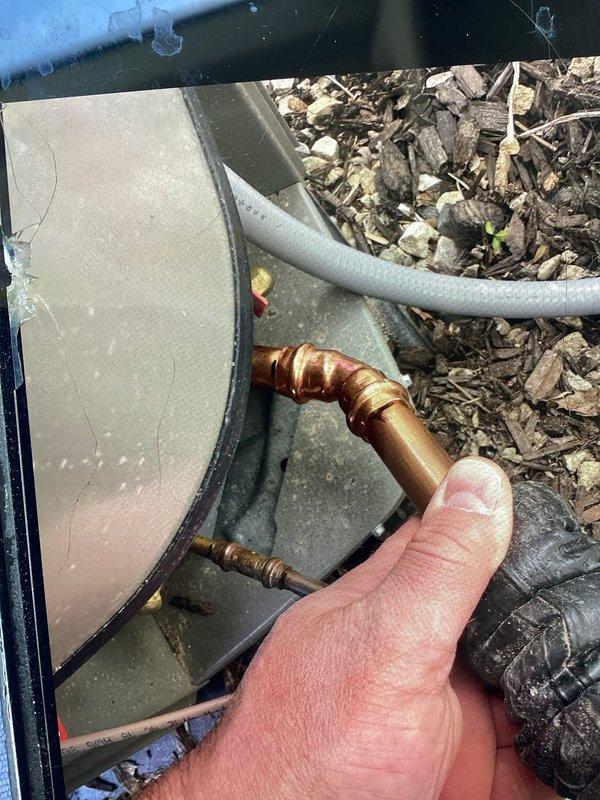 Responded to no cooling call on newly installed HVAC system where contractor accidentally drove nail through refrigerant line during construction work. Located punctured copper refrigerant line at outdoor unit, confirmed active refrigerant leak, and coordinated repair to restore system operation. Documented damage to refrigerant piping with photos showing compromised copper fitting and surrounding installation area for warranty and repair documentation purposes.