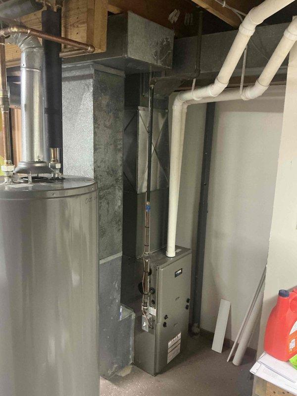 Responded to no-heat emergency call for 15-year-old furnace with failed blower motor. Completed full system replacement installation in basement mechanical room, including new furnace unit with metal ductwork connections and refrigerant line routing. Existing water heater remained in place during furnace changeout, with all new equipment positioned on concrete floor and properly integrated with existing duct distribution system throughout the residence.
