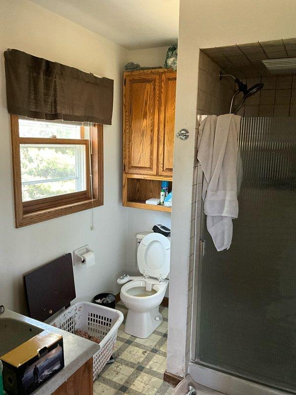 Conducted comprehensive restoration site walk-through and documented property conditions following fire damage. Photographed intact bathroom area showing functional fixtures and existing HVAC considerations, as well as severely fire-damaged structure with compromised roof, exposed framing, and extensive fire retardant contamination requiring full system assessment for restoration planning.