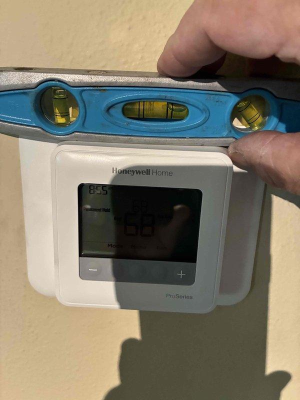 Responded to callback regarding recent installation quality concerns. Verified thermostat level alignment using torpedo level and documented exterior condensate line penetration with expanding foam sealant. Photographed both items for quality assurance review and advised customer that invoice will be mailed following this no-charge service visit.