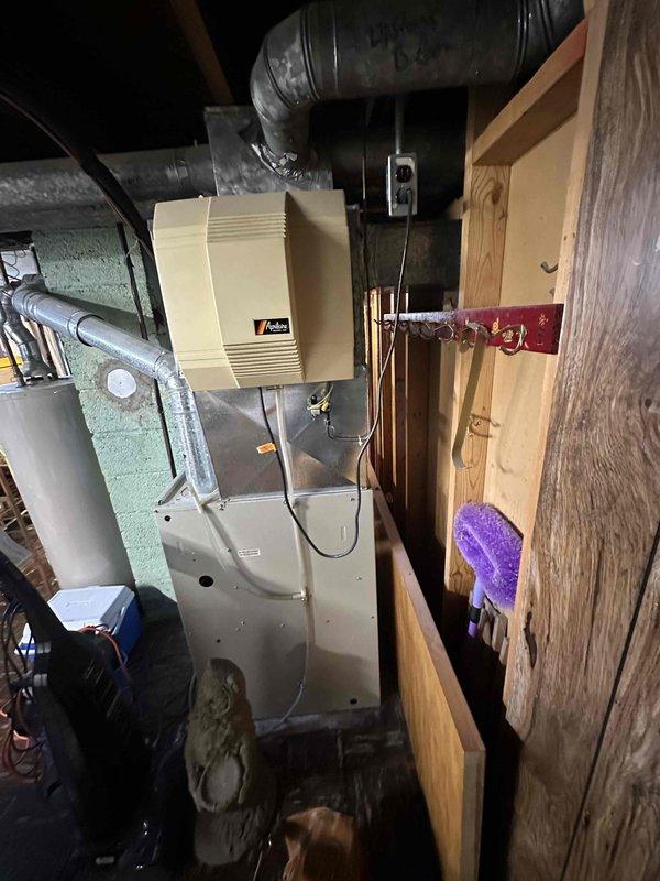 Provided comprehensive estimate for complete HVAC system replacement including furnace and air conditioning unit, both over 20 years old. Assessed existing natural gas furnace with humidifier attachment in basement utility area and evaluated outdoor condensing unit positioned on gravel pad against brick exterior. Documented current system configuration including ductwork, refrigerant lines, and electrical connections to determine replacement specifications and scope of work.