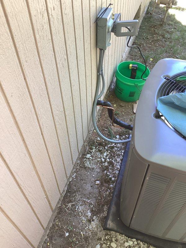 Completed installation of new air conditioning system with evaporator coil at property with no existing equipment. Installed outdoor condensing unit on gravel pad adjacent to building exterior with proper clearances, mounted electrical disconnect box on exterior wall with conduit run to unit, and positioned indoor air handler with copper refrigerant line connections on concrete floor in mechanical space. System fully installed, tested, and operational.