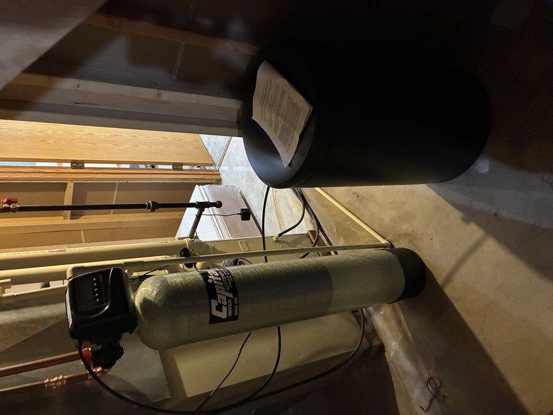Installed water softener system in utility space with proper mounting brackets and secure positioning. Replaced toilet angle stop valve at wall connection point with chrome-finished fixture and connected braided flexible supply line. Completed tub trim installation. All plumbing connections tested for proper operation and verified no leaks present at angle stop valve or water softener connections.