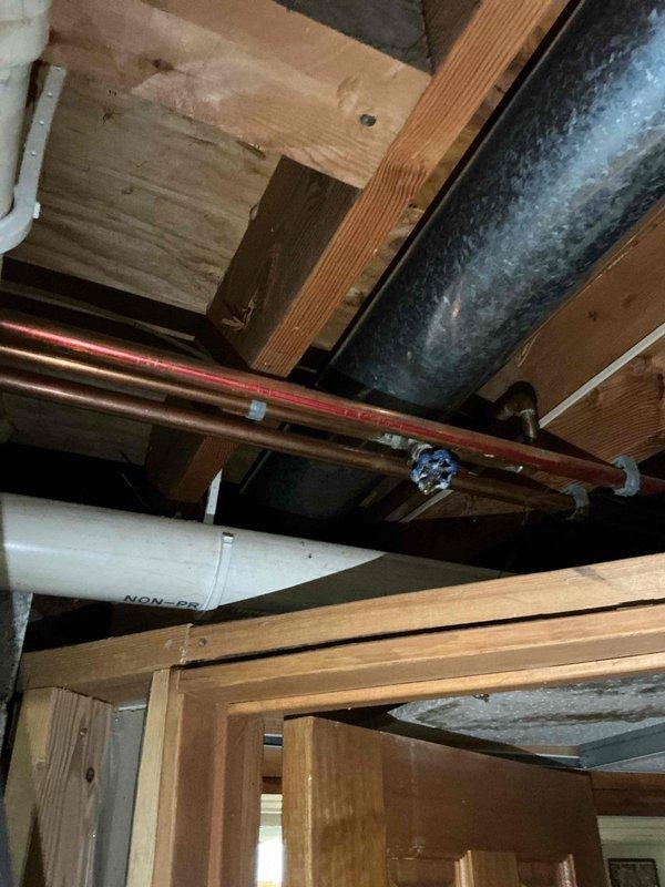 Conducted site assessment and provided estimate for replacement of interior water shut-off valve and exterior hose spigot. Inspected existing copper supply line running through ceiling cavity and evaluated current valve condition, noting blue-handled shut-off requiring replacement. Documented mechanical chase area showing copper plumbing infrastructure, HVAC ductwork, and structural framing to determine scope of work and access requirements for proposed fixture replacements.