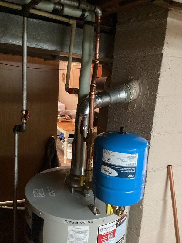 Completed installation of new residential water heater in basement utility room. Installation included proper venting with metallic duct, copper supply line connections, integration with existing blue expansion tank, and verification of all plumbing connections per manufacturer specifications and local code requirements.