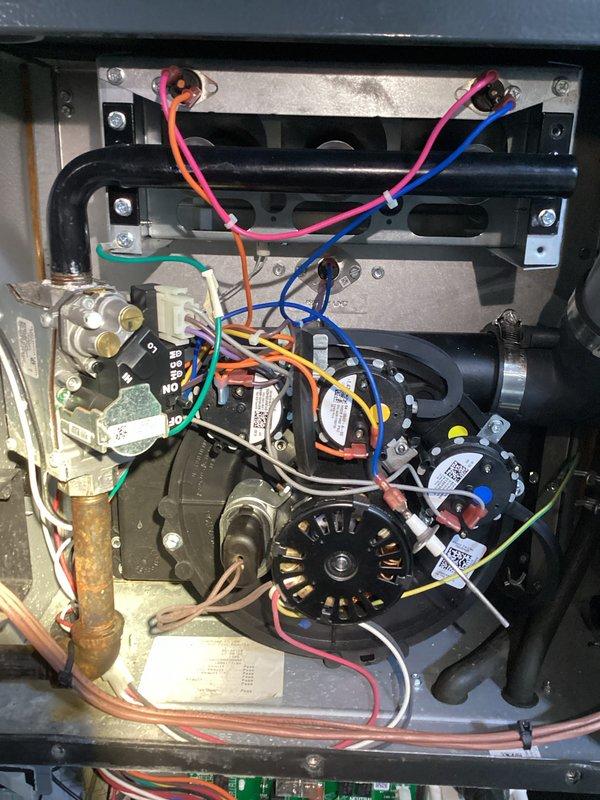 Completed comprehensive furnace and air conditioning tune-up including thorough cleaning and inspection of all accessible components. Removed access panels to examine internal systems, verified proper operation of blower motor, gas valve assembly, pressure switches, and electrical connections. Documented equipment condition with photos showing HVAC system installation with PVC condensate drain lines, ductwork connections, and internal components including motor assembly and copper refrigerant lines with normal patina development.