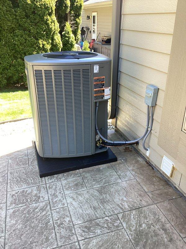 Completed spring HVAC system installation including new Lennox air conditioning condenser unit and evaporator coil. Positioned outdoor condenser on stamped concrete pad with protective base, secured refrigerant line sets and condensate drain, and installed electrical disconnect box with flexible conduit routing to exterior wall. All mechanical connections completed and system staged for final electrical hookup by licensed electrician to complete power wiring and startup procedures.