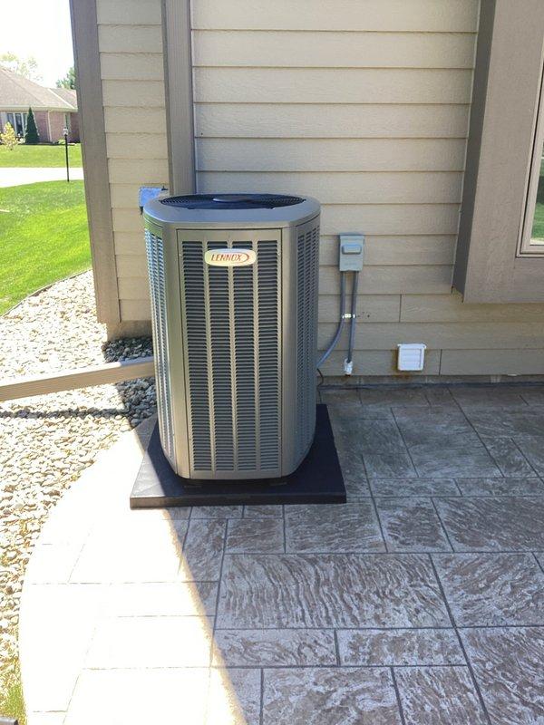 Completed spring HVAC system installation including new Lennox air conditioning condenser unit and evaporator coil. Positioned outdoor condenser on stamped concrete pad with protective base, secured refrigerant line sets and condensate drain, and installed electrical disconnect box with flexible conduit routing to exterior wall. All mechanical connections completed and system staged for final electrical hookup by licensed electrician to complete power wiring and startup procedures.