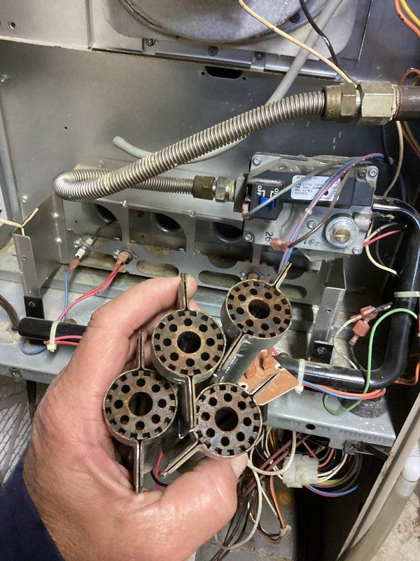 Completed furnace and air conditioning tune-up maintenance on residential HVAC system. Removed and inspected gas burner assembly, which consisted of four circular brass burner heads with proper hole patterns and central openings. Verified gas valve operation, checked all electrical connections and wiring throughout the unit, and inspected flexible gas line and fittings for proper installation and safety. Cleaned burner assembly, reassembled unit, and confirmed proper system operation. Provided estimate for duct cleaning services per customer inquiry.