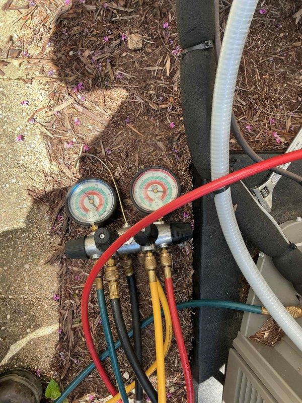 Responded to service call for outdoor heat pump unit. Performed comprehensive tune-up maintenance including refrigerant system diagnostics using manifold gauges and pressure testing equipment. Unit showed signs of age and weathering with visible exterior repair patch, but system operated within acceptable parameters upon completion of service and testing.