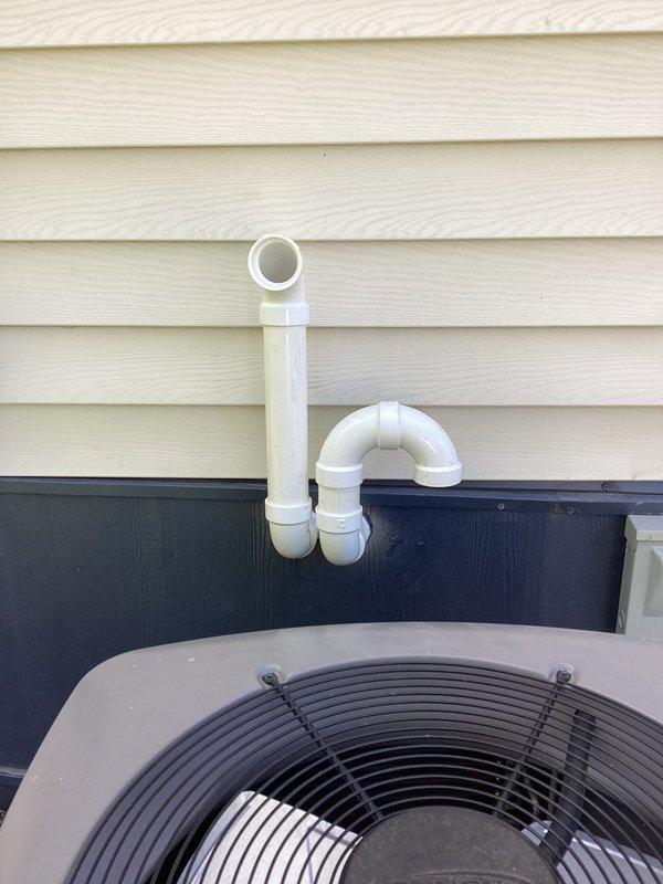 Completed installation of LP (liquid propane) furnace system at residential property. Installed new furnace unit with associated condensate drainage system utilizing white PVC piping with proper trap configuration mounted on exterior wall near existing HVAC equipment. All components properly secured and drainage system routed to ensure efficient moisture removal from heating system operation.