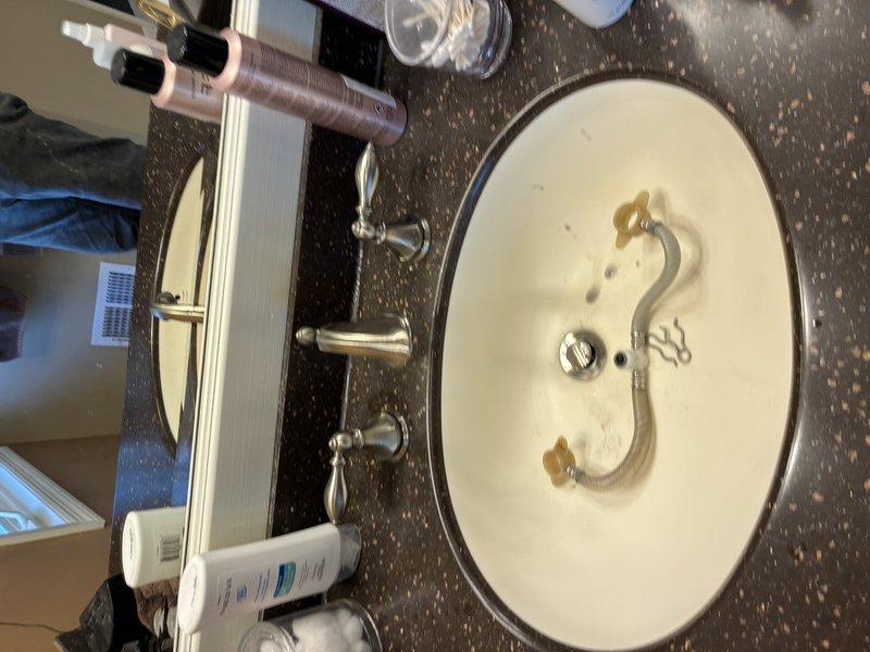 Responded to a follow-up service call for a leaking bathroom sink faucet. Upon arrival, diagnosed water leakage occurring at the handle area beneath the countertop when either hot or cold water supply was activated. Inspected the chrome dual-handle faucet assembly mounted on the vanity and identified the source of the leak. Completed necessary repairs to resolve the water leakage issue and restore proper function to the fixture.