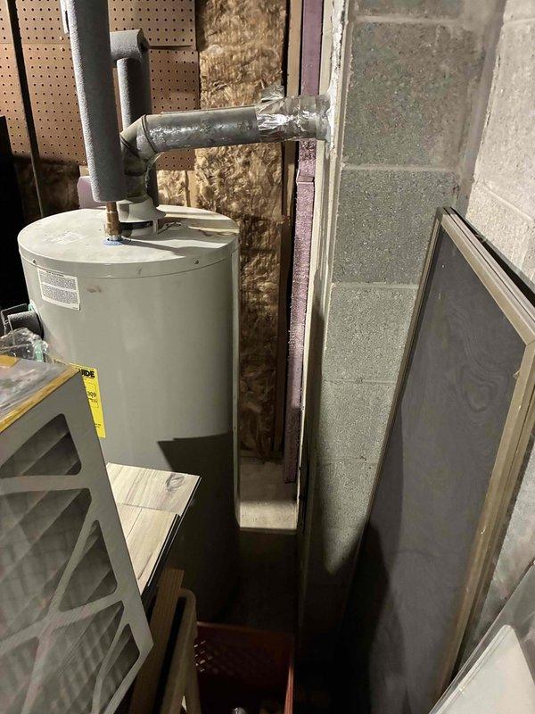 Conducted on-site assessment of existing natural gas water heater in residential utility room for replacement estimate. Documented current equipment configuration including water heater installation, venting system, and surrounding HVAC components. Measured and photographed equipment dimensions and clearances to determine proper replacement unit specifications and installation requirements.