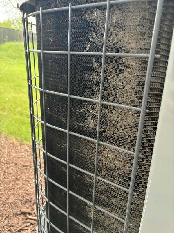 Performed comprehensive tune-up service on residential outdoor condensing unit. Upon arrival, found condenser coils and protective wire guard heavily soiled with accumulated dirt, dust, and debris significantly restricting airflow. Cleaned condenser coils, fins, and protective mesh guard to restore proper airflow and system efficiency, completed standard maintenance procedures including electrical connections inspection and refrigerant level verification.