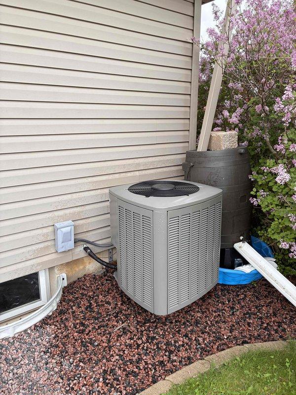 Completed annual air conditioning tune-up on outdoor condensing unit. Performed standard maintenance inspection, verified electrical readings using digital multimeter showing 4.098 microfarads capacitance within normal operating range, and confirmed system operational status. Unit accessible with adequate clearance despite nearby landscaping.