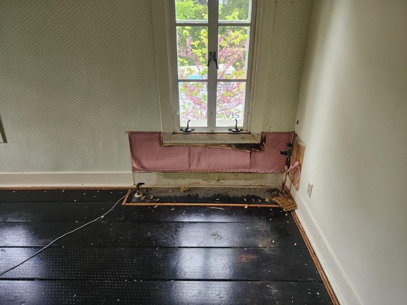 Removed existing hydronic radiators from residential property in preparation for boiler system installation, with radiators to be reinstalled upon completion of the heating system upgrade. Work included careful disconnection and removal of radiator units from multiple rooms, including hallway closet area and bedroom with visible water damage to walls and flooring. Documented pre-existing conditions including deteriorated baseboards, exposed insulation, and compromised subflooring where radiator connections were located.