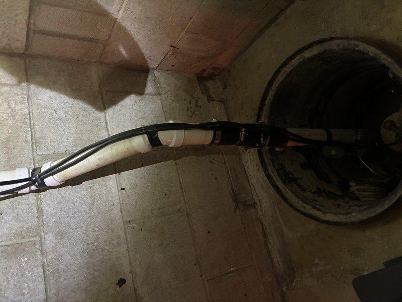 Conducted comprehensive site assessment of existing sump pump system located in basement utility area. Evaluated current pump installation, discharge piping configuration, and basin condition to prepare estimate for complete sump pump replacement and battery backup system installation. Documented deteriorated basin conditions, corroded mechanical components, and aged discharge piping showing mineral buildup and significant wear. Identified need for new primary sump pump unit with enhanced capacity, installation of battery backup system to ensure continuous operation during power outages, and replacement of compromised mounting hardware and discharge assembly.